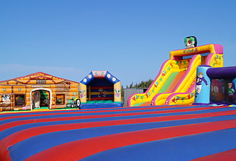 Colorful Inflatable Bouncy Castle And Slide Park Under Blue Sky