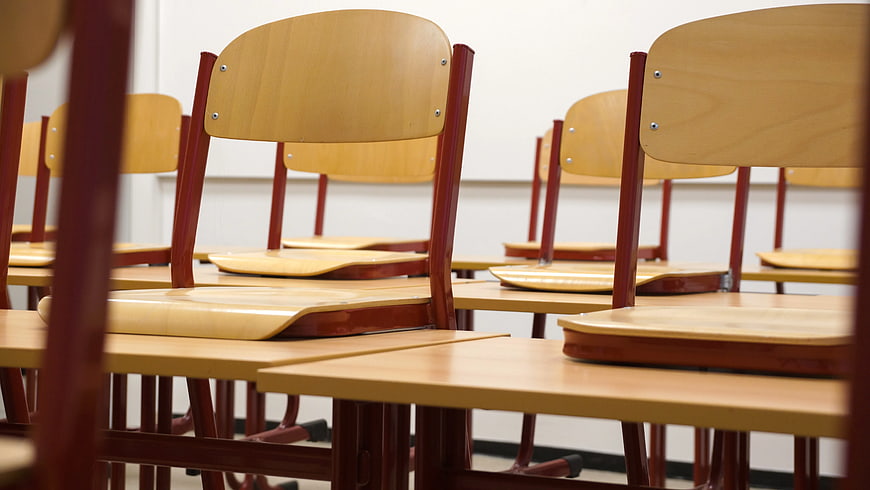 Empty wooden school chairs and desks in classroom