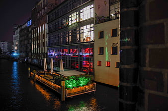 Night view of illuminated canal buildings and floating deck in Berlin