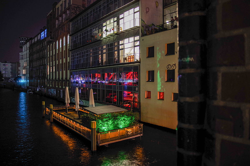 Night view of illuminated canal buildings and floating deck in Berlin