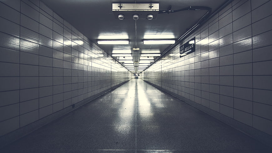 Empty tiled subway tunnel with fluorescent lights