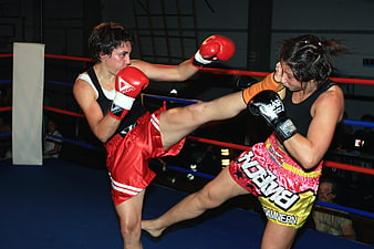 Two female kickboxers sparring in a boxing ring