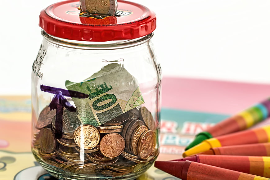 Glass jar with coins and banknotes for children's savings
