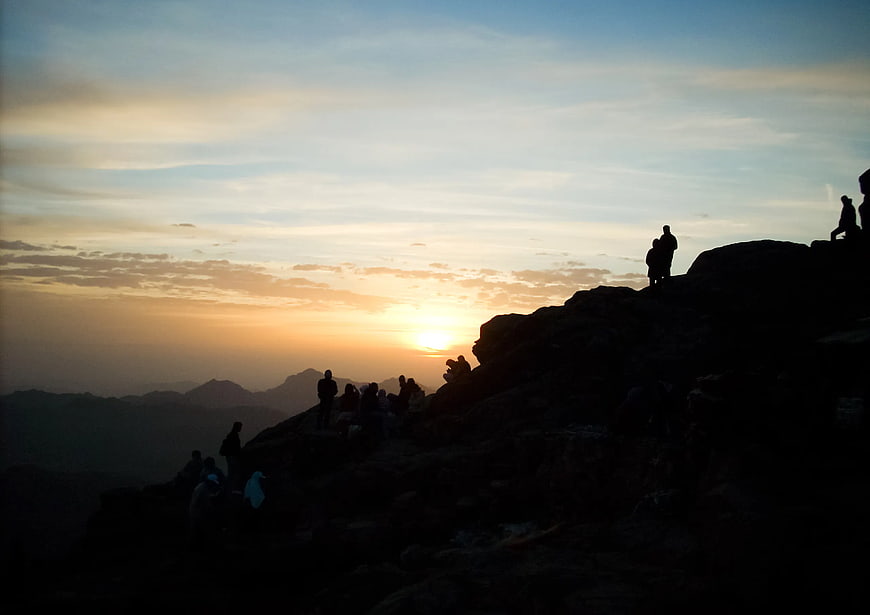 Silhouettes of Hikers Watching Sunrise on Mountain Peak