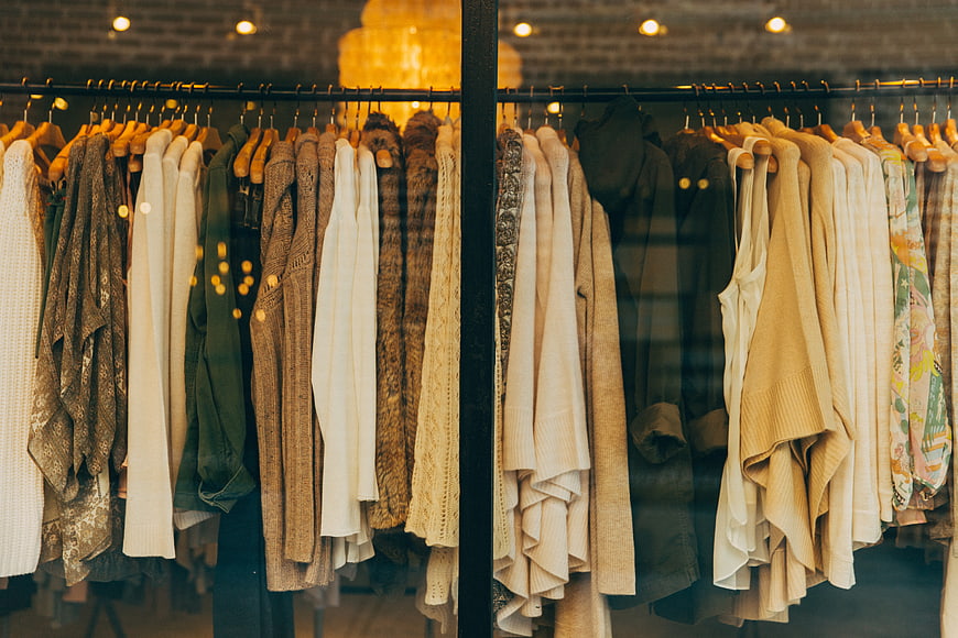 Clothing rack in boutique store window with warm lighting