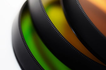 Close-up of black camera lens filters with green and orange glass