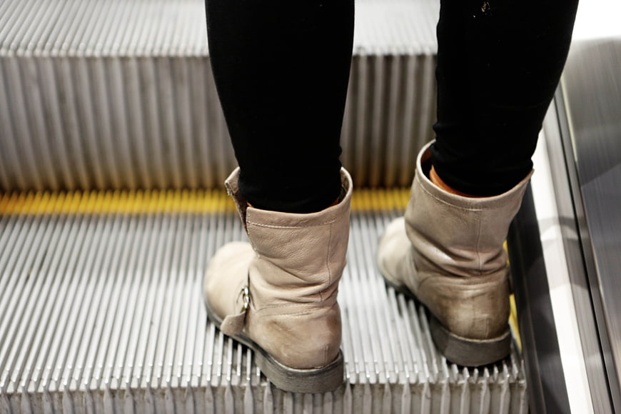 Close-up of beige boots on escalator steps