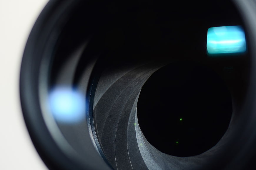 Close-up of camera lens aperture blades with blue light reflection