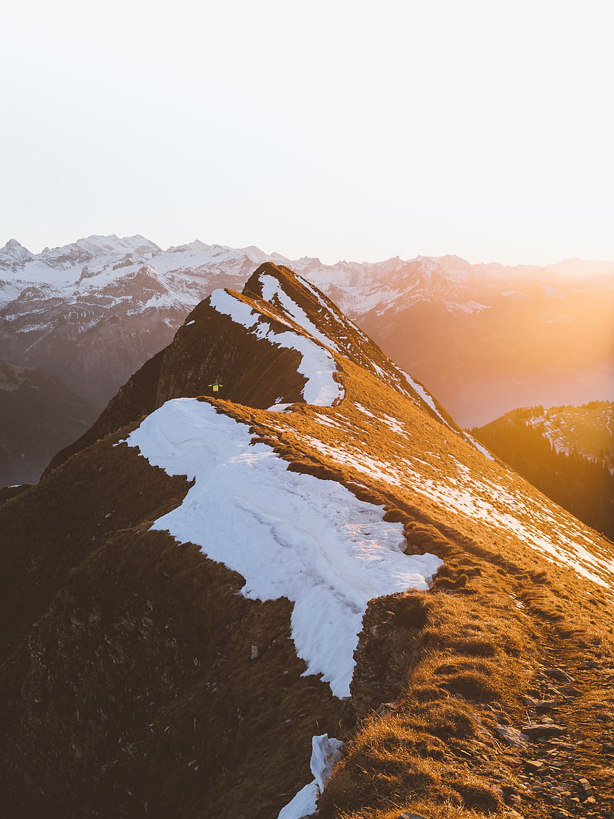 Hiker on Snowy Mountain Ridge at Golden Hour