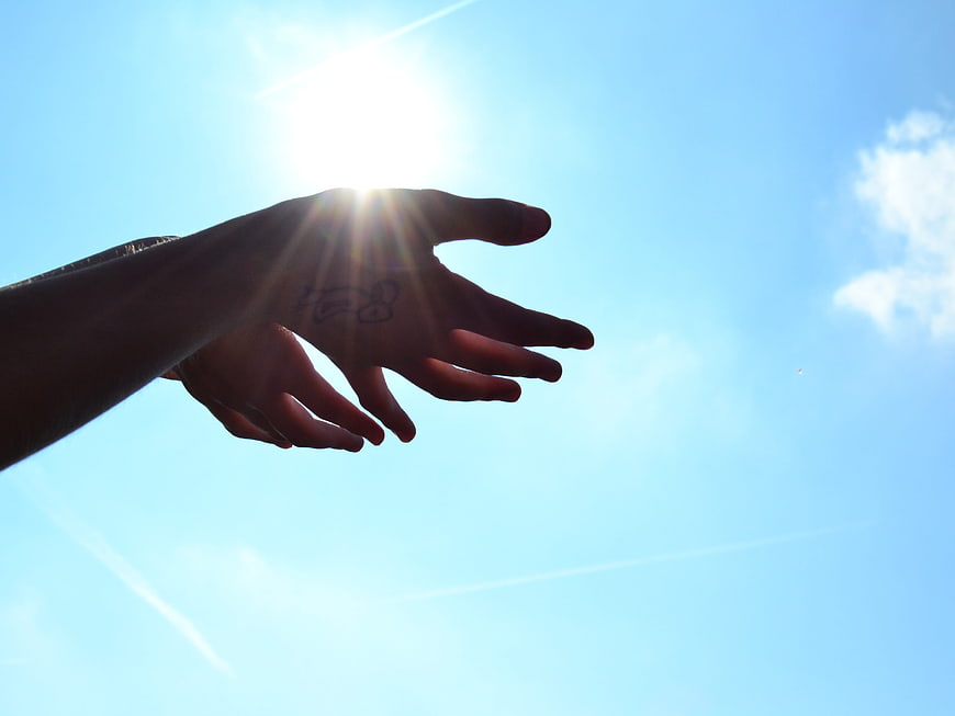 Silhouette of Hands Reaching for Sun in Blue Sky