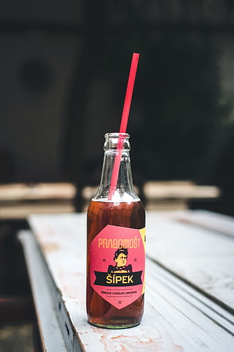 Glass Bottle of Pink Lemonade with Red Straw on Wooden Table
