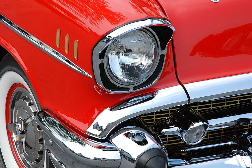 Close-up of Classic Red Car Headlight and Chrome Bumper