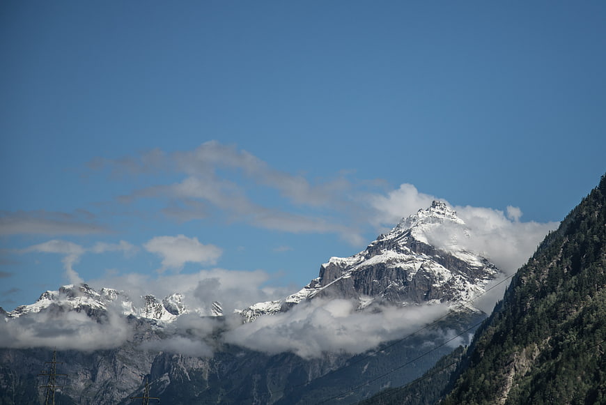 Snowy Swiss Alps mountain peak with clouds and blue sky