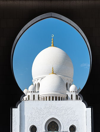 White Mosque Dome Framed by Dark Archway Against Blue Sky