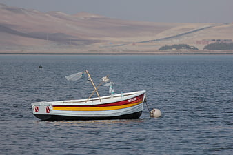 Traditional fishing boat anchored in calm bay with hills