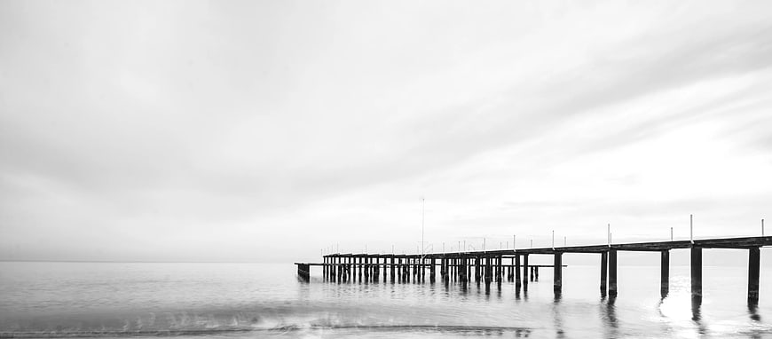 Minimalist Black and White Wooden Pier on Calm Sea