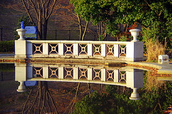 Stone bridge with geometric railing reflected in calm water