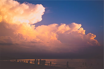Dramatic Sunset Clouds Over Silhouetted Beach Crowd