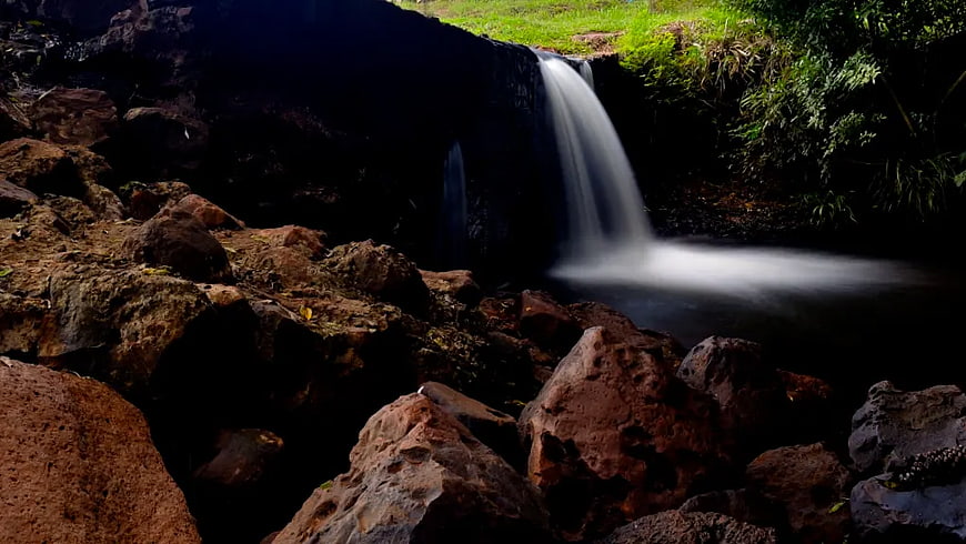 Serene Waterfall Flowing Over Rocks in Lush Forest