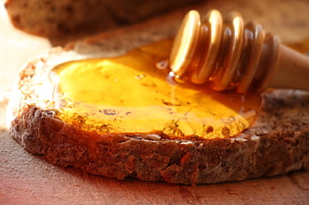 Close-up of golden honey drizzled on rustic brown bread