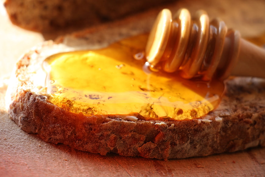 Close-up of golden honey drizzled on rustic brown bread