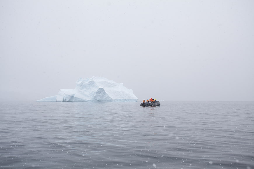 Zodiac boat with tourists near iceberg in Antarctica