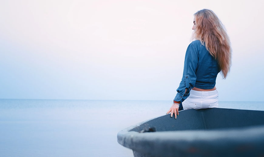 Woman in Denim Sitting on Boat Looking at Calm Sea