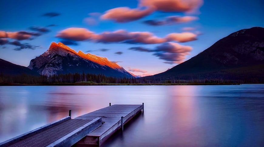 Serene Lake Dock at Sunset with Glowing Mountain Peaks