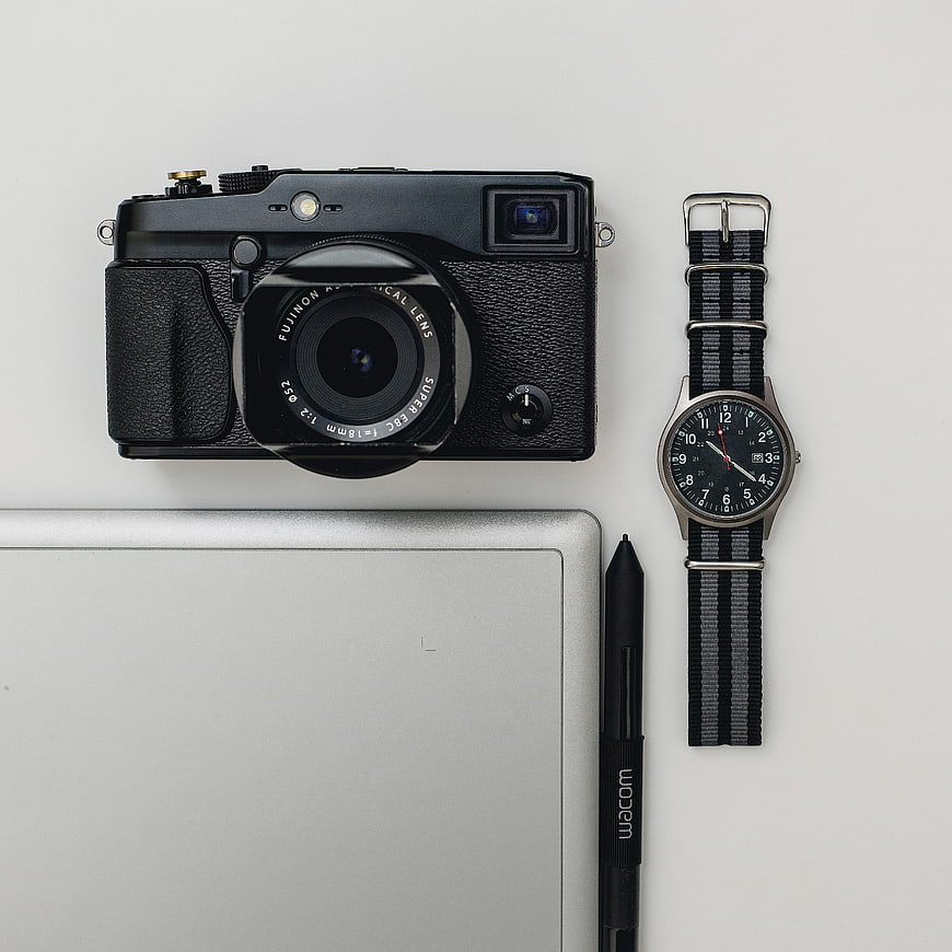 Flat lay of vintage camera, watch, and digital tablet on white background
