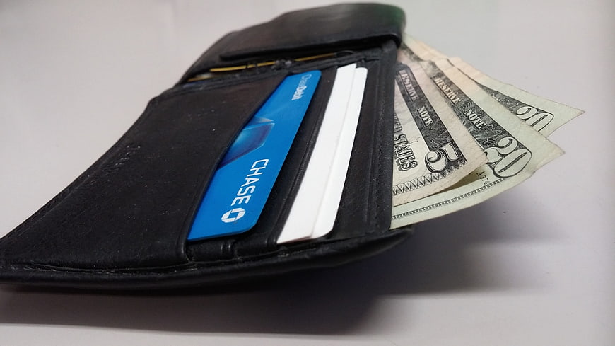 Black leather wallet with cash and credit card on white background