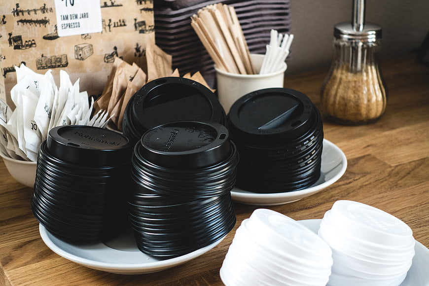 Stacks of black and white coffee cup lids on wooden counter