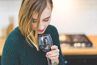 Woman smelling red wine in cozy kitchen setting