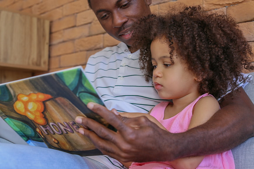 Father Reading Picture Book to Toddler Daughter Indoors