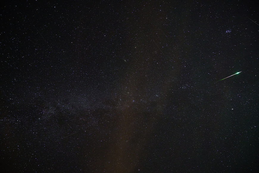 Green Meteor Streaking Across Starry Night Sky With Milky Way