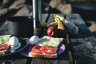 Healthy camping breakfast with sandwiches and fruit on wooden table