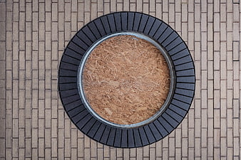 Top-down view of circular wooden planter on paved ground