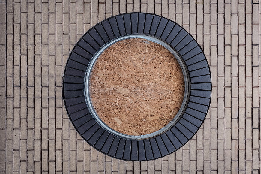 Top-down view of circular wooden planter on paved ground