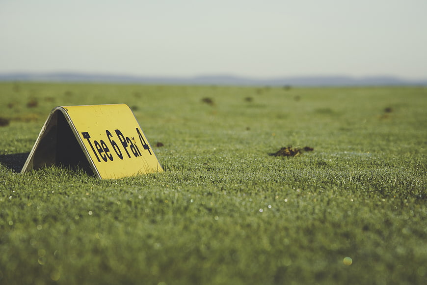 Yellow Golf Tee Marker Sign on Green Grass Field