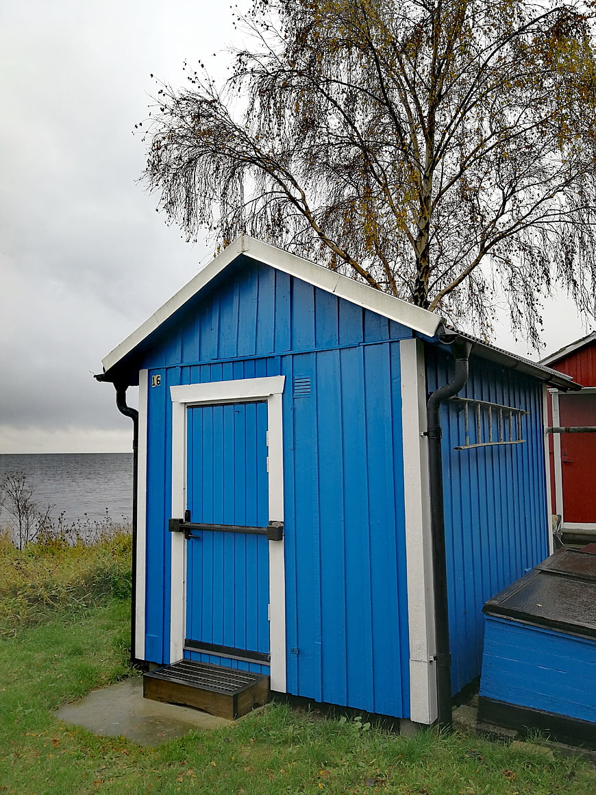 Blue wooden boathouse by the sea in autumn