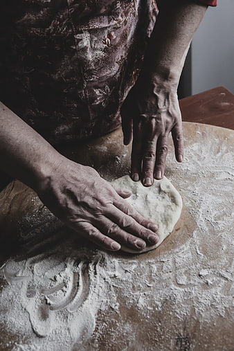 Close-up of hands kneading dough on floured wooden board