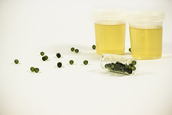 Green Urine Sample Jars and Capsules on White Background