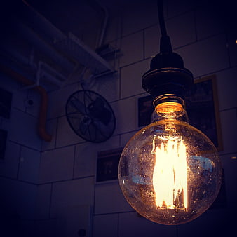Vintage Edison light bulb glowing in dark industrial interior