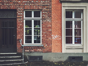 Red brick building facade with white windows and graffiti