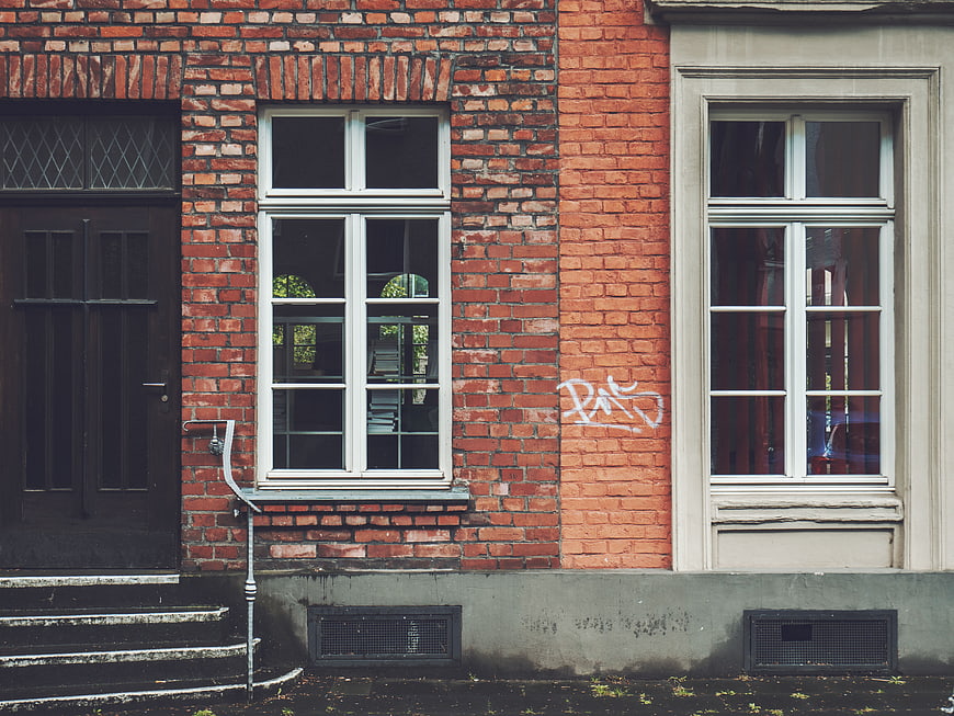 Red brick building facade with white windows and graffiti