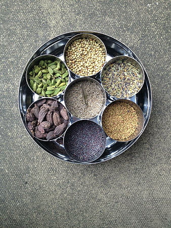 Traditional Indian spice assortment in metal bowls on a stone surface