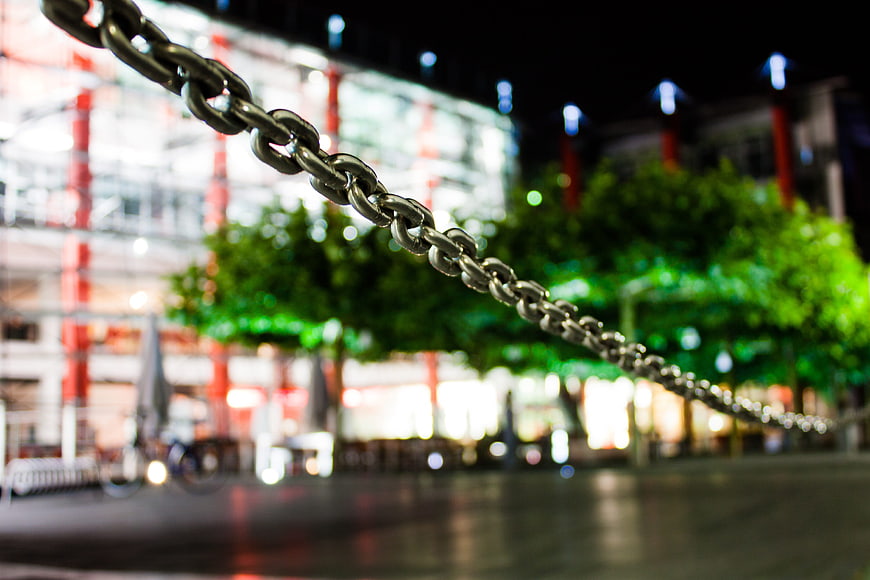 Metal chain barrier with blurred city lights at night