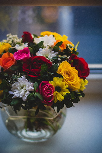 Colorful bouquet of roses and daisies in a glass vase