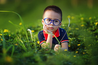 Cute Asian Boy with Glasses Lying in Green Grass