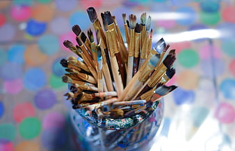 Used paintbrushes in a jar with colorful bokeh background