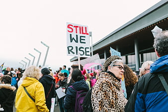 Woman in Leopard Coat at Protest Rally with Still We Rise Sign